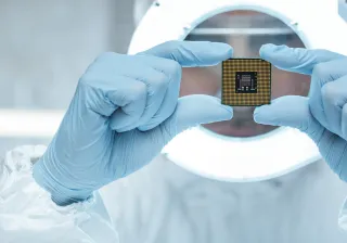 A closeup of a cleanroom lab worker&#039;s hands holding a computer chip