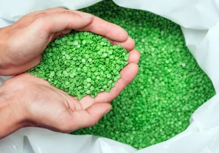 A closeup photo of a pair of hands scooping up recyclable plastic pellets.