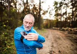 A photo of a jobber is adjusting the volume of his smartphone, which he is listening to with earbuds.