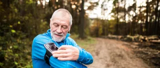 A photo of a jobber is adjusting the volume of his smartphone, which he is listening to with earbuds.
